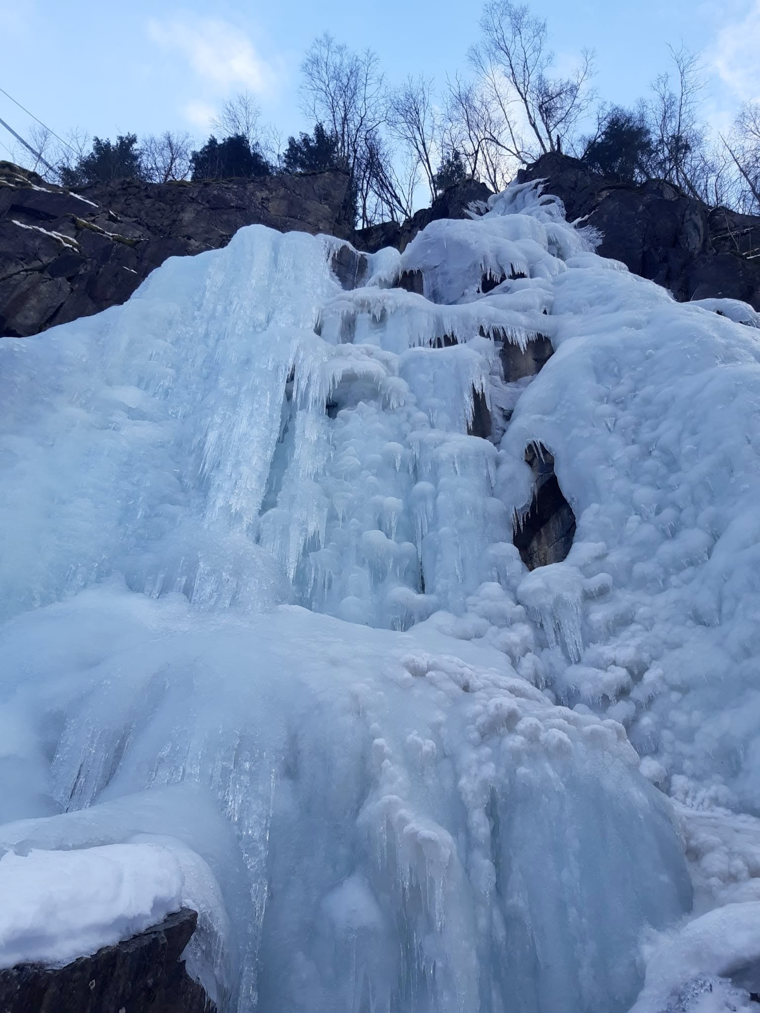 Ice formations on Vemorkbrufoss Vest viewed from below, with rock and trees above the route